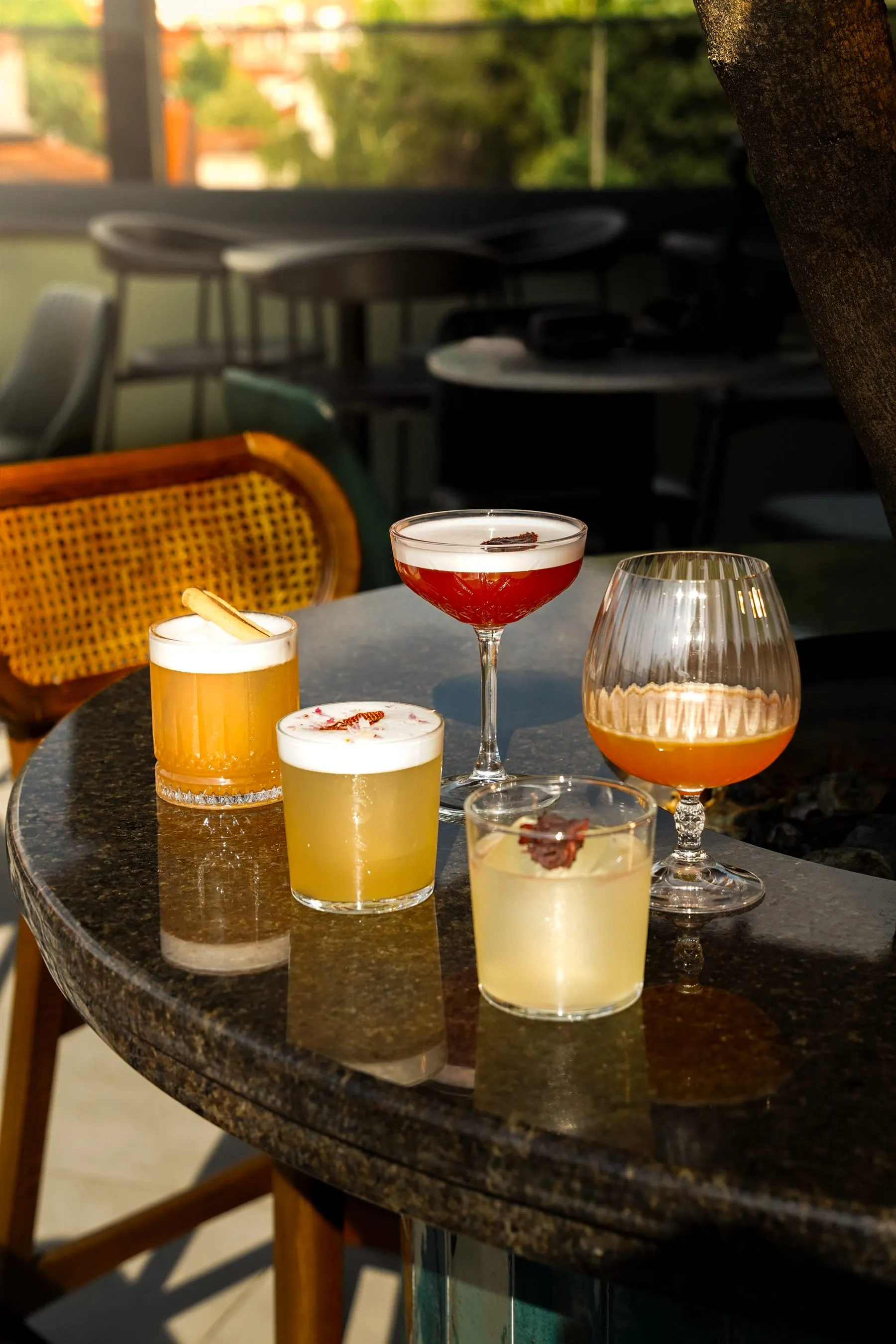 Five signature cocktails lined up on the terrace table at golden hour